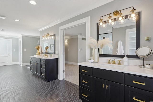 bathroom with baseboards, ornamental molding, two vanities, recessed lighting, and a sink