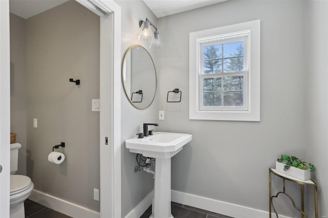 bathroom featuring tile patterned floors, toilet, baseboards, and a sink