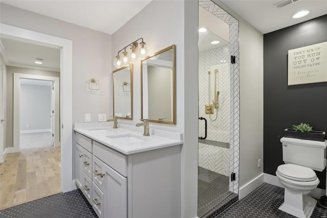 bathroom featuring double vanity, a stall shower, toilet, and a sink