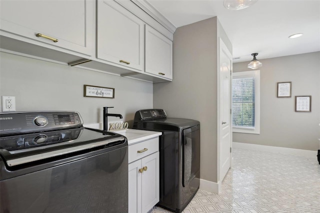 clothes washing area with washer and dryer, cabinet space, baseboards, and a sink