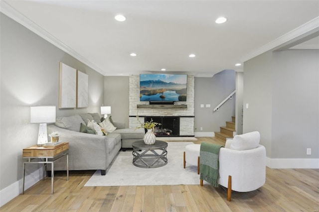 living room featuring a large fireplace, crown molding, baseboards, and wood finished floors