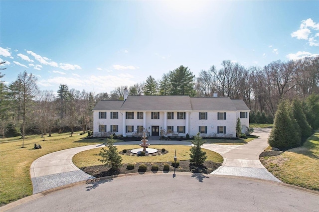 view of front of property with curved driveway and a front yard