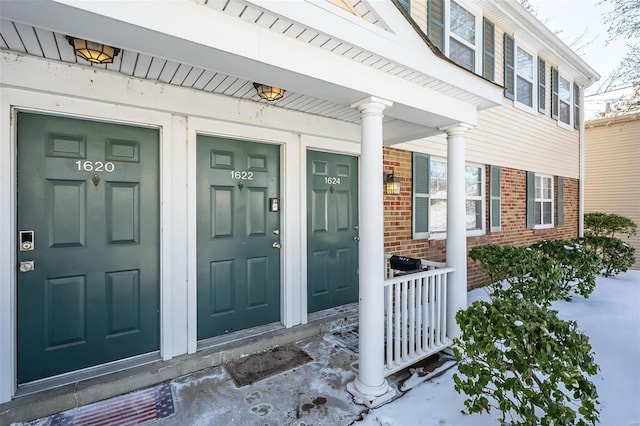 doorway to property with a porch and brick siding