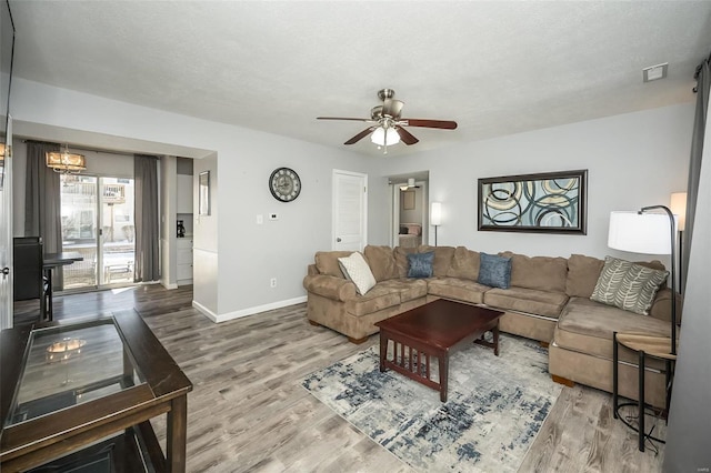 living area featuring visible vents, a ceiling fan, a textured ceiling, wood finished floors, and baseboards