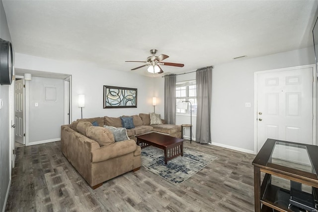 living area with dark wood-style floors, baseboards, and a ceiling fan