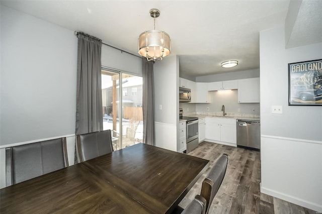 unfurnished dining area with dark wood finished floors, a sink, and baseboards