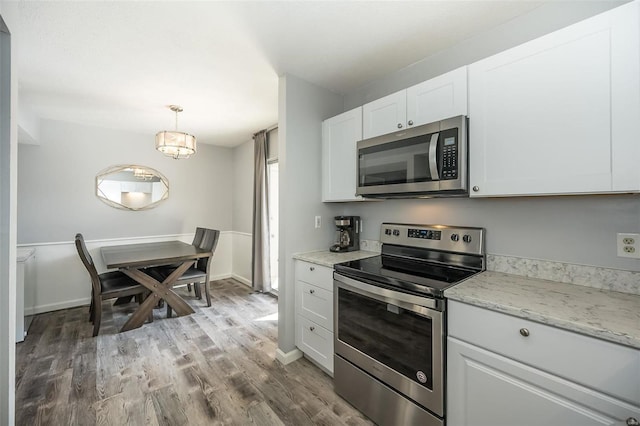 kitchen with white cabinets, light wood-style flooring, pendant lighting, and stainless steel appliances