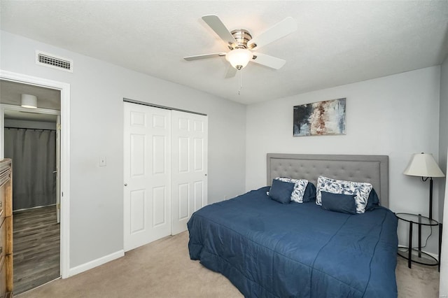 bedroom with light colored carpet, a ceiling fan, visible vents, baseboards, and a closet