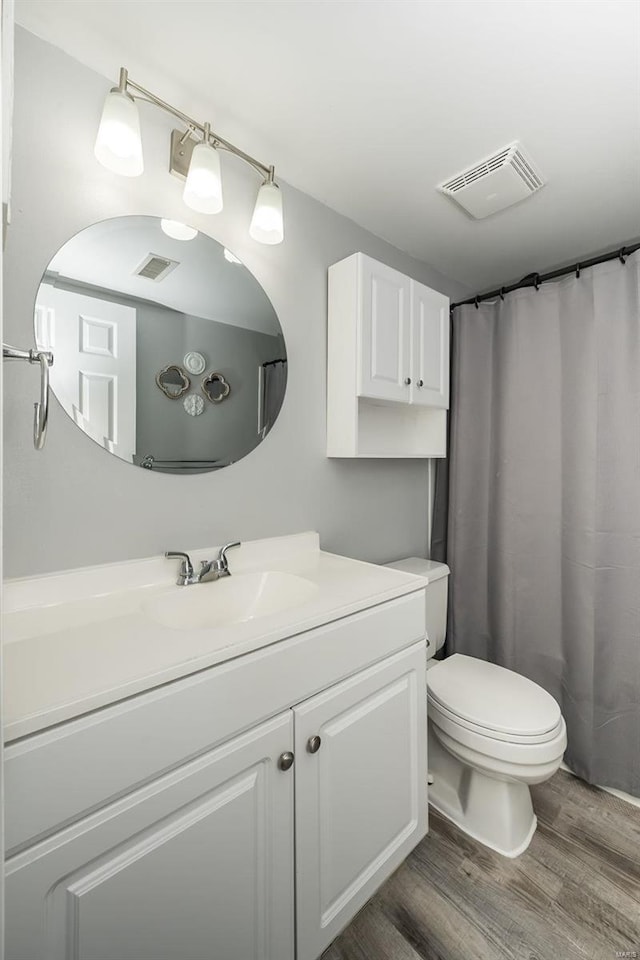 full bath with visible vents, vanity, toilet, and wood finished floors