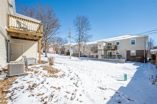 snowy yard featuring a balcony and cooling unit