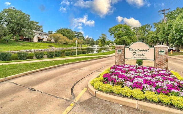 community sign featuring a water view and a lawn