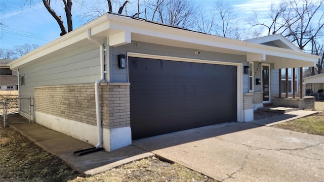 view of side of property with driveway, brick siding, and an attached garage