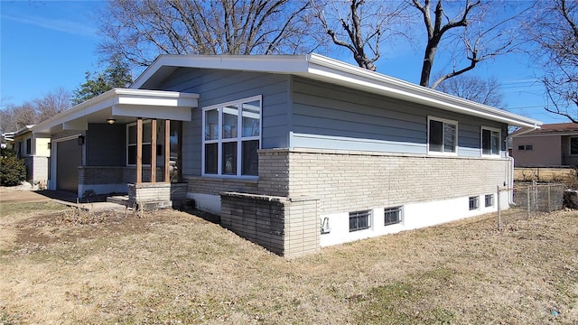 view of property exterior with covered porch, a yard, and brick siding