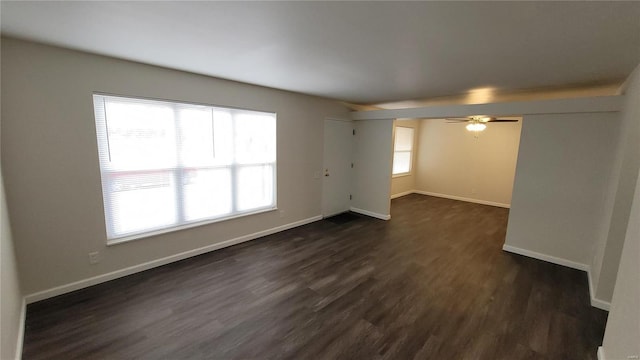 unfurnished room featuring ceiling fan, baseboards, and dark wood-type flooring