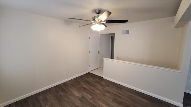 spare room with dark wood-style floors, baseboards, visible vents, and ceiling fan
