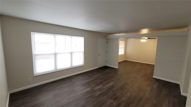unfurnished room with a ceiling fan, baseboards, and dark wood-type flooring