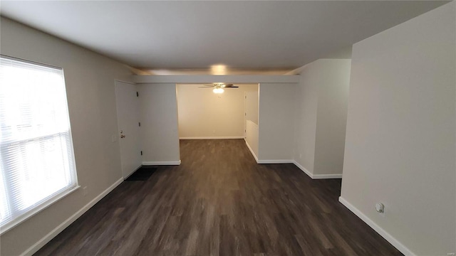 spare room with ceiling fan, baseboards, and dark wood-style flooring