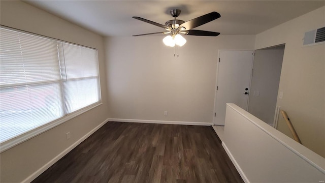 spare room featuring a ceiling fan, baseboards, visible vents, and dark wood-style flooring