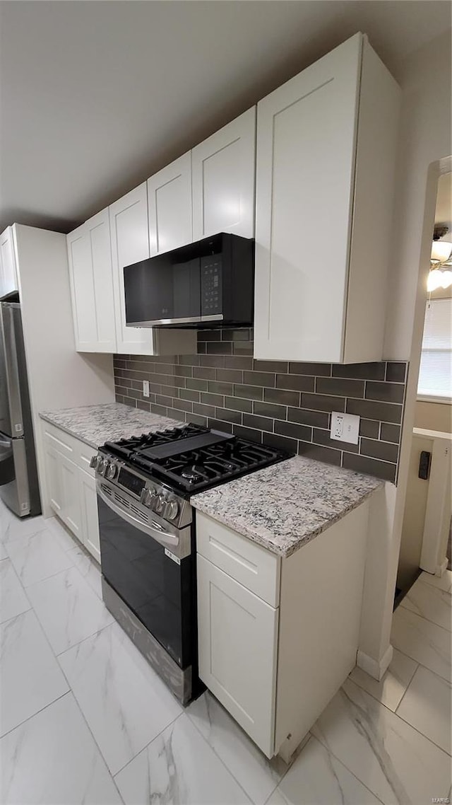 kitchen with marble finish floor, white cabinetry, black microwave, and gas stove