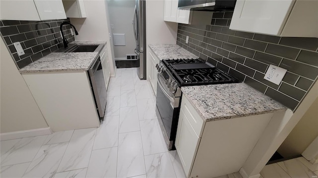kitchen featuring a sink, white cabinets, marble finish floor, appliances with stainless steel finishes, and light stone countertops
