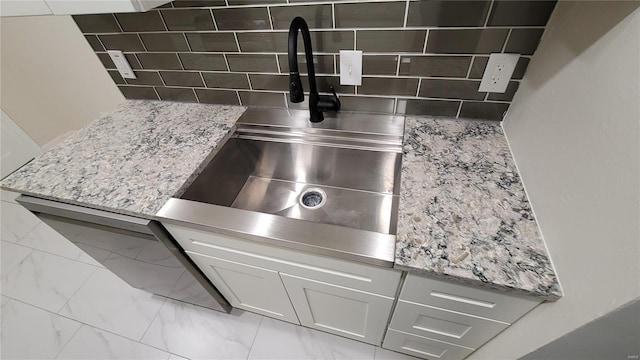 details featuring a sink, decorative backsplash, and light stone countertops