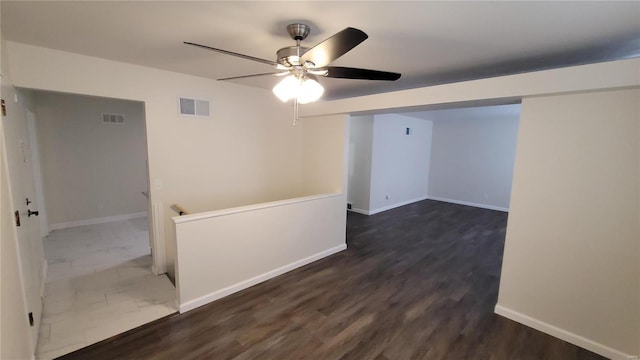 unfurnished room featuring dark wood-style floors, visible vents, and baseboards