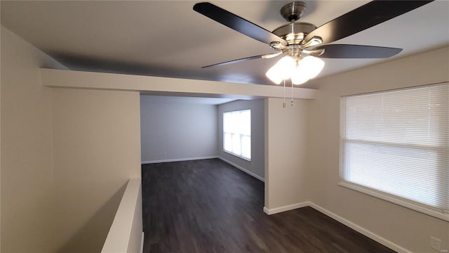 unfurnished room with a ceiling fan, baseboards, and dark wood-type flooring