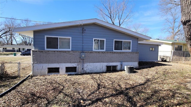 view of side of home featuring central AC unit, fence, and brick siding