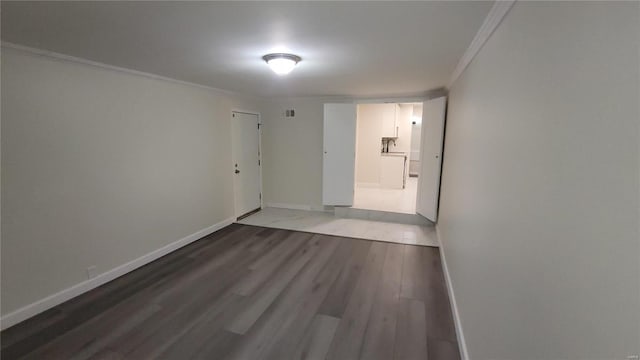 empty room with crown molding, baseboards, and wood finished floors