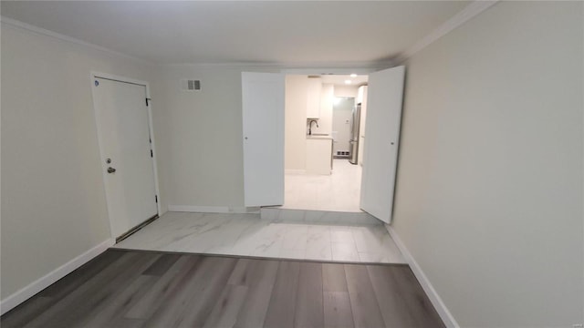 interior space with visible vents, crown molding, baseboards, and wood finished floors