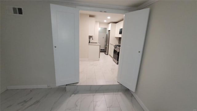 hallway with marble finish floor, a sink, visible vents, and baseboards