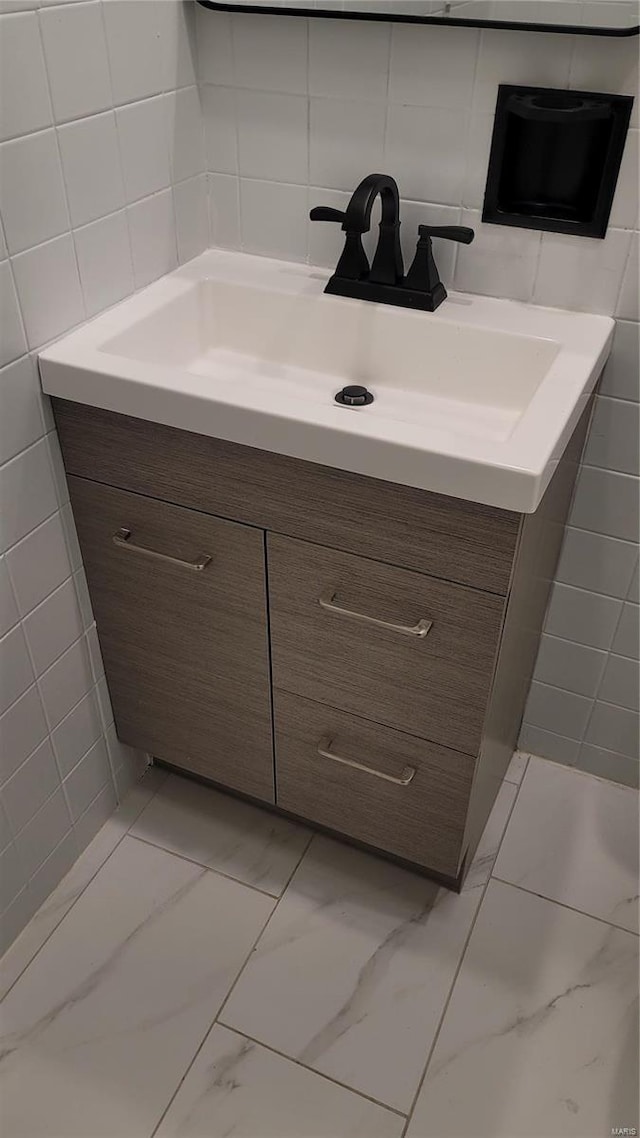 bathroom featuring marble finish floor, tile walls, and vanity