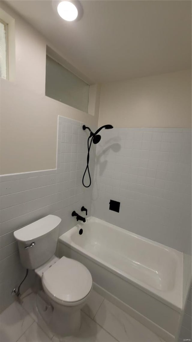 full bath featuring toilet, marble finish floor, shower / bathing tub combination, and tile walls