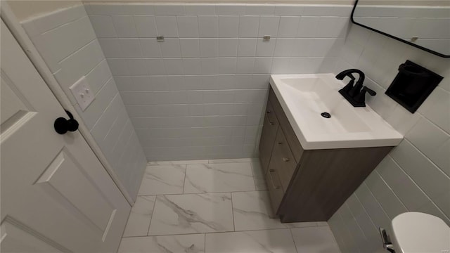 half bathroom featuring tile walls, marble finish floor, and vanity