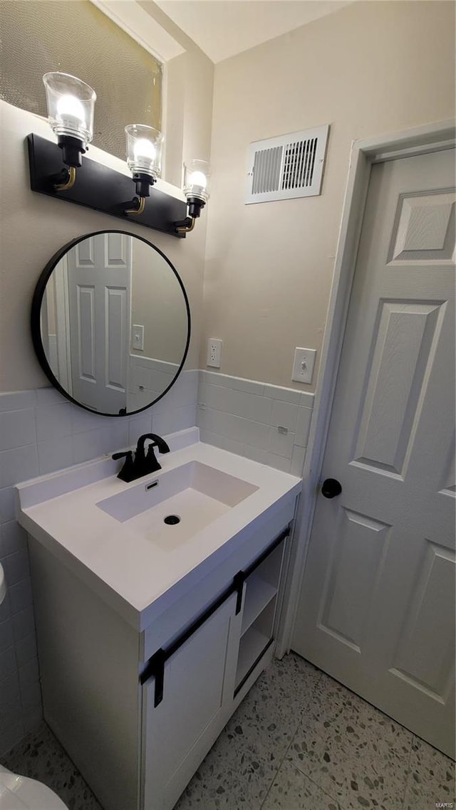 bathroom featuring a wainscoted wall, visible vents, tile walls, and vanity