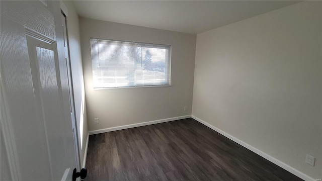 empty room featuring dark wood-style floors and baseboards