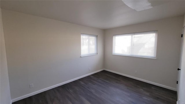 spare room featuring dark wood-style flooring and baseboards