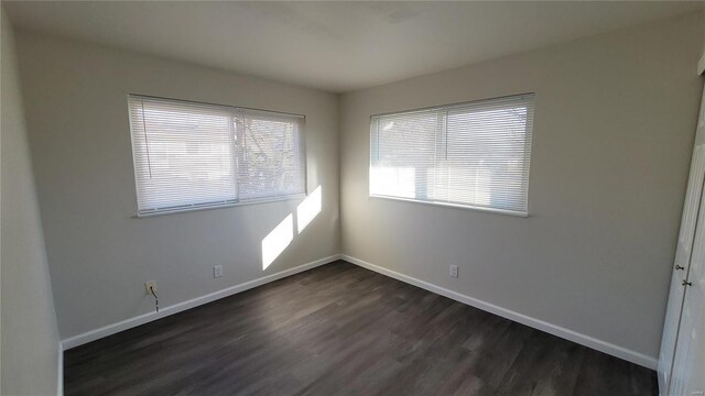 unfurnished room featuring dark wood finished floors and baseboards