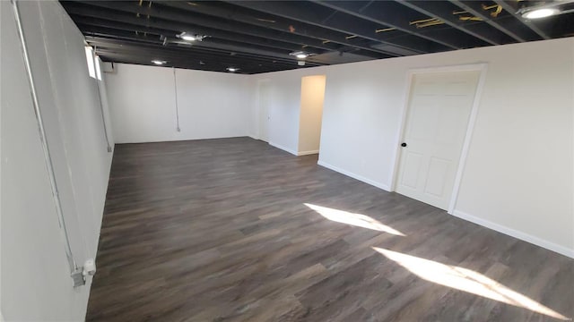 finished below grade area with dark wood-style floors and baseboards