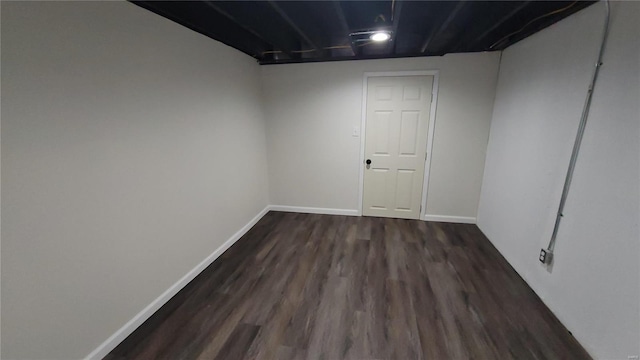 unfurnished room featuring dark wood-type flooring and baseboards
