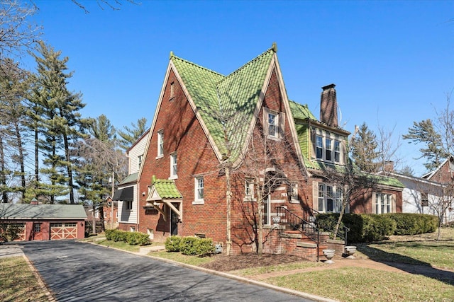 view of side of home featuring a yard, an outbuilding, brick siding, and a chimney