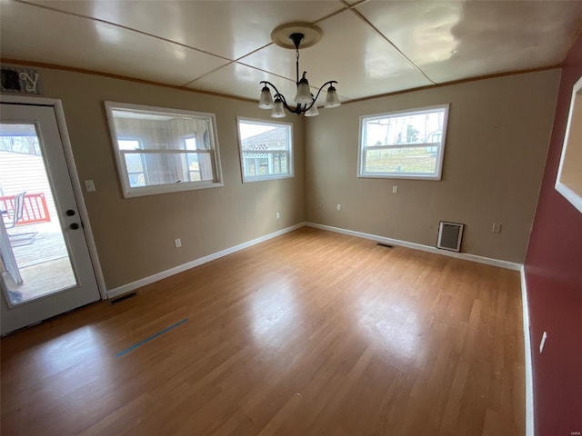 interior space featuring ornamental molding, light wood finished floors, visible vents, and baseboards