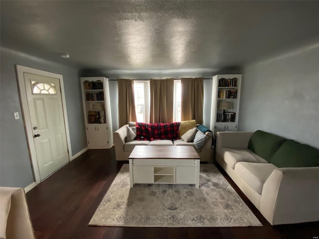 living room with a textured ceiling, baseboards, and wood finished floors