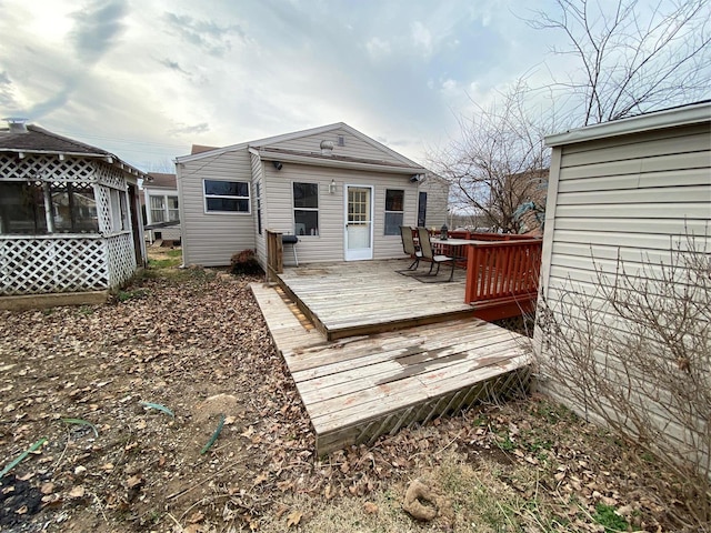 rear view of house featuring a sunroom and a deck