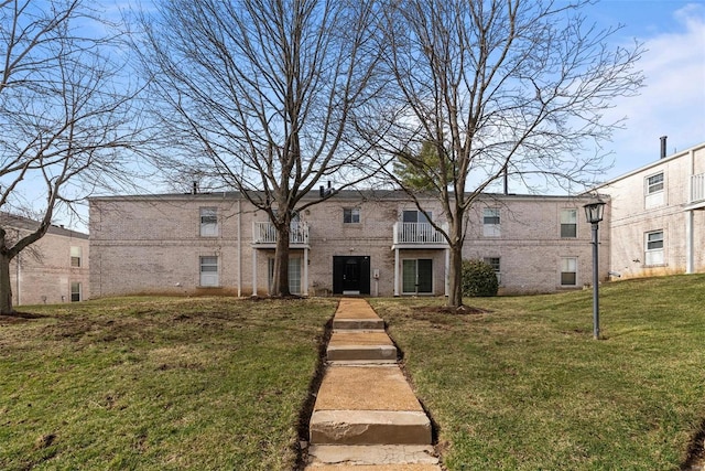 townhome / multi-family property with a front lawn and brick siding