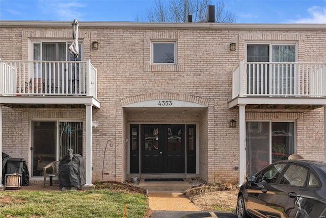 entrance to property with brick siding and a balcony