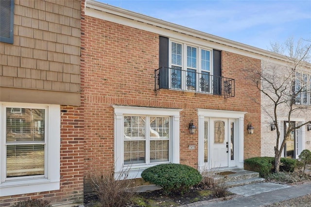 view of front of house featuring brick siding and a balcony