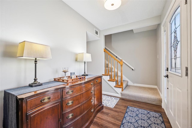 entrance foyer featuring dark wood-style flooring, visible vents, stairway, and baseboards