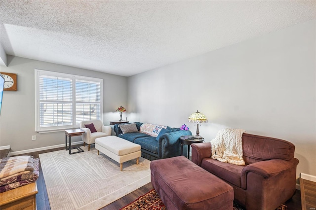 living area featuring a textured ceiling, dark wood-style flooring, and baseboards