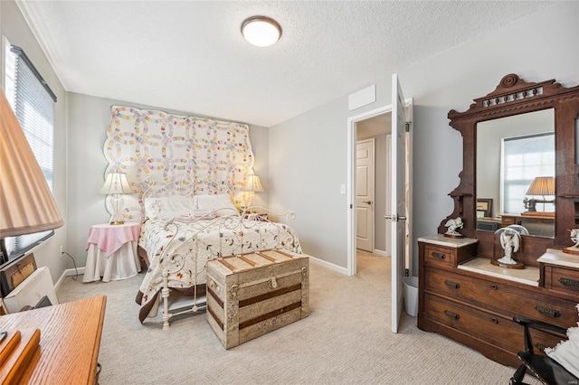 bedroom with light carpet, baseboards, and a textured ceiling